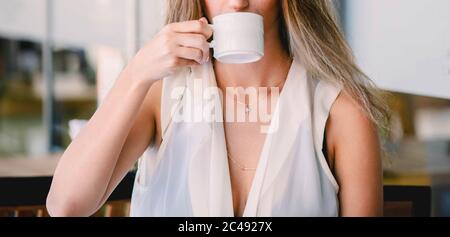 Café. Belle fille de boire du thé ou du café au café. Femme modèle de beauté avec la tasse de boisson chaude. Tons chauds. Banque D'Images