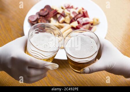 Prise de vue en grand angle de deux personnes avec de la bière gants en plastique en quarantaine Banque D'Images