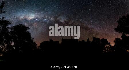 Magnifique photo panoramique de silhouettes d'arbres et de bâtiments sous une nuit étoilée Banque D'Images