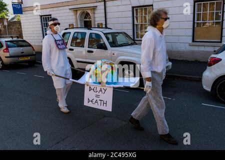 LEOMINSTER, ROYAUME-UNI - 25 JUIN 2020 : les manifestants pour le changement climatique se réunissent dans le cadre d'une journée de manifestations nationales, avec pour objectif l'avertissement « Delay = Death » à Leominster, Herefordshire, Royaume-Uni, le 25 juin 2020. Programmé pour coïncider avec la publication d'un rapport de la Commission parlementaire britannique sur le changement climatique, le cortège sombre composé de personnages costumés portant des costumes de sablier portait un modèle de terre bandé aux portes des députés locaux. Crédit : Jim Wood/Alay Live News Banque D'Images