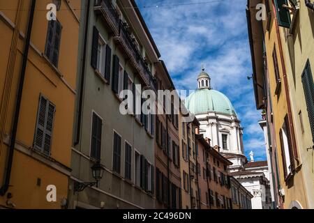 Descendre la rue dans la vieille ville de Brescia. Vue sur les façades multicolores des bâtiments résidentiels et le dôme de la cathédrale (Duomo Nuovo). Banque D'Images