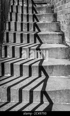 Image noire et blanche des ombres projetées de quelques balustrades sur des marches en pierre formant un motif. Banque D'Images