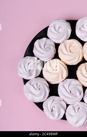 guimauves colorées sur une assiette noire. doux zephyr maison ou guimauve. Pose à plat. Vue de dessus Banque D'Images