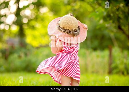 Petite fille en robe d'été et grand chapeau de paille se tient avec son dos, espace pour le texte Banque D'Images