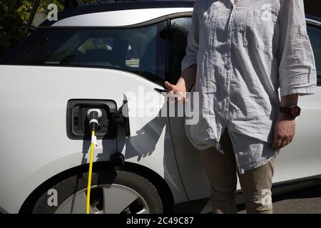 Gros plan d'une femme avec un smartphone en charge voiture électrique Banque D'Images