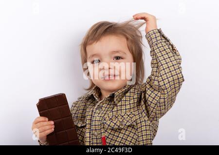 Adorable bébé garçon mangeant tenant une barre de chocolat avec des marques de morsure Banque D'Images