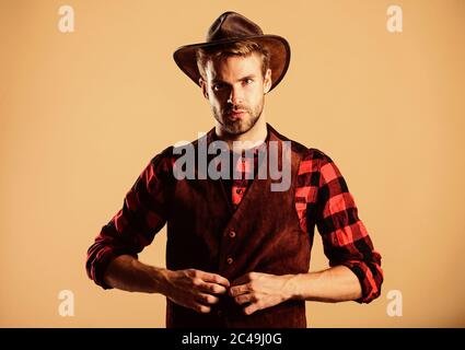 Port de Cowboy hat. La vie dans l'Ouest. Homme cowboy non rasé beige background. Guy non rasé en chapeau de cowboy. Beau macho barbu. American Cowboy. Norme de beauté. Exemple d'une véritable masculinité. Banque D'Images