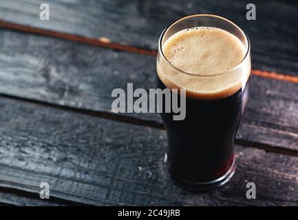 Un verre de bière artisanale sombre porte-bière sur une table en bois dans un pub avec espace d'imitation Banque D'Images