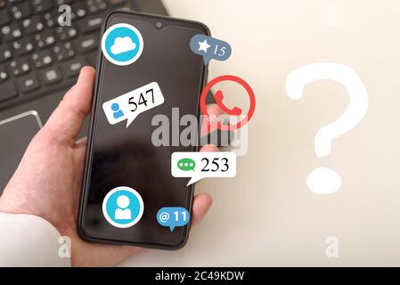 La main utilise un smartphone et un hologramme de diverses icônes, dont un point d'interrogation. Concepts de réseaux sociaux.