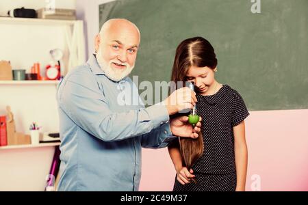 recherche en laboratoire. Analyse et synthèse. Élargir la connaissance du monde. Échantillon biologique. Enseignant mûr regarder dans la loupe tube sur la chaux. Petite fille explorer la tranche de fruits. École. Microscopie. Banque D'Images