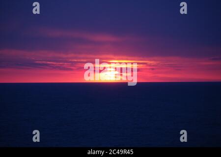 Séquence d'images d'un coucher de soleil, coucher de soleil rouge vif sur mer sombre avec nuages sombres Banque D'Images