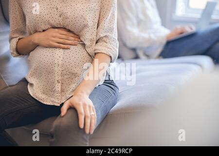 Femme en chemise et jeans touchant son ventre de grossesse Banque D'Images