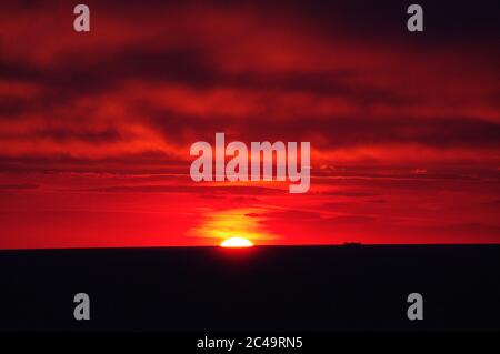 Séquence d'images d'un coucher de soleil, coucher de soleil rouge vif sur mer sombre avec nuages sombres Banque D'Images