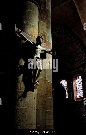 Statue de Jésus Christ crucifixion sur un fond de mur de briques dans une église sombre avec vitraux. France Banque D'Images