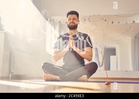 Jeune homme serein méditant dans le studio de yoga Banque D'Images