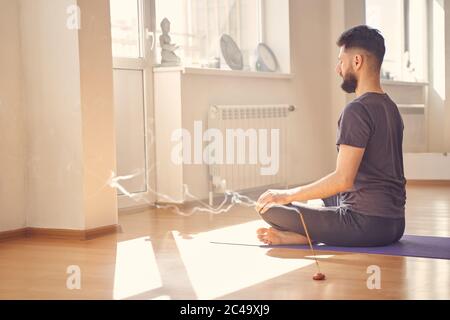 Jeune homme barbu méditant en position de yoga Banque D'Images
