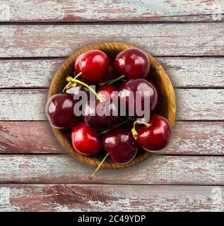 Fruits à la cerise dans un bol en bois. Cerises avec espace de copie pour le texte. Vue de dessus. Contexte des cerises. Cerises mûres et savoureuses sur fond de bois. Banque D'Images