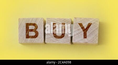 Concept commercial. Cubes en bois avec mot acheter sur fond jaune Banque D'Images