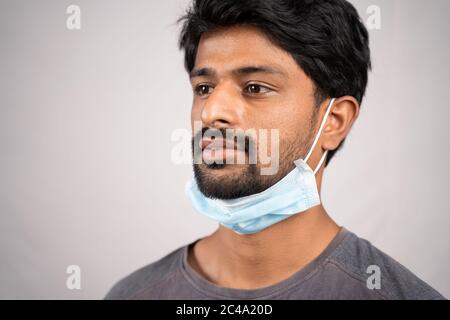 concept montrant la manière inappropriée d'utiliser des masques faciaux pendant la crise du coronavirus ou du covid-19 - jeune homme portant un médecin au cou sur un fond isolé Banque D'Images