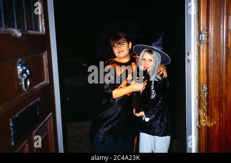 Les enfants trick ou traiter tenant le chat noir à Halloween Surrey, Angleterre Banque D'Images
