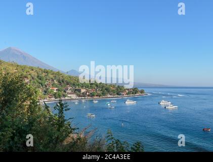 Lagon calme avec bateau à voile et bâtiments en forêt sur le flanc d'une colline. Bateau safari de plongée ancré dans la baie de Jemeluk Banque D'Images