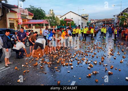 Penang, Malaisie - 8 février 2017 : les dévotés se préparant à l'arrivée du char d'argent en écrasant la noix de coco sur la route avant pendant la Thaïlande Banque D'Images