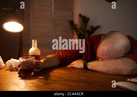 Homme mature dormant à la table après avoir bu des boissons alcoolisées pendant la fête Banque D'Images