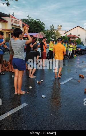 Penang, Malaisie - 8 février 2017. Un dévot hindou se préparant à écraser la noix de coco sur la route. C'est pour se préparer à l'arrivée du Dieu chari Banque D'Images