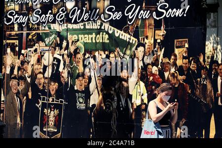 Une femme portant un masque facial protecteur passe devant un panneau sur le Palace Bar dans le Temple Bar de Dublin, les pubs et les bars d'hôtel fonctionnant comme des restaurants peuvent commencer à rouvrir au public le lundi 29 juin, conformément à la phase 3 du Gouvernement de l'assouplissement des restrictions de la COVID-19. Banque D'Images