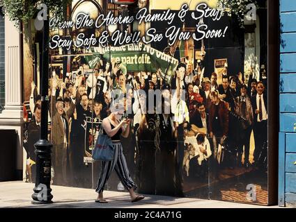 Une femme portant un masque facial protecteur passe devant un panneau sur le Palace Bar dans le Temple Bar de Dublin, les pubs et les bars d'hôtel fonctionnant comme des restaurants peuvent commencer à rouvrir au public le lundi 29 juin, conformément à la phase 3 du Gouvernement de l'assouplissement des restrictions de la COVID-19. Banque D'Images