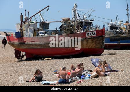 Bains de soleil parmi les bateaux de pêche. Les visiteurs de Hastings n'ont aucun problème avec la distance sociale le jour le plus chaud de l'année jusqu'à ce que le Royaume-Uni hea Banque D'Images