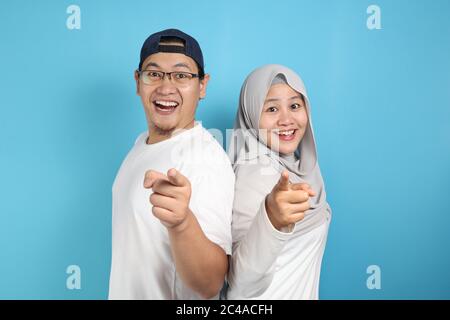 Portait de heureux asiatique couple musulman souriant et pointant vers l'appareil photo, mari et femme embrassant plein d'amour, concept de famille Banque D'Images