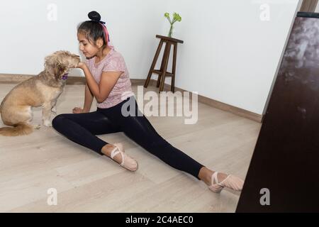 Une petite fille se fait dorloter son chien dans son salon tout en faisant des exercices Banque D'Images