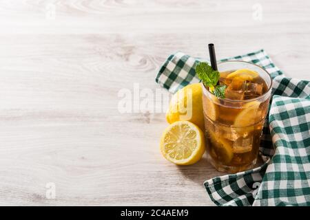 Thé glacé avec citron dans le verre et glace sur table en bois blanc. Espace de copie Banque D'Images