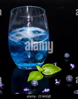 Un seul verre de gin et de tonique, fait avec un tonique bleu aromatisé aux bleuets et des bleuets frais pour Banque D'Images