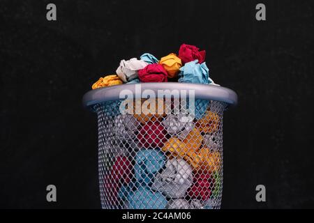Des boules de papier colorées froissés dans une poubelle. Gros plan. Banque D'Images