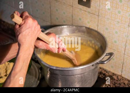 Polenta de cuisine, cuisine italienne traditionnelle, typique, faite avec de la semoule de maïs et de l'eau. Une femme cuit de la polenta, tournant une cuillère en bois dans le chou-fleur. Déjeuner Banque D'Images