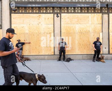 Manhattan, New York, États-Unis - 7 juin 2020 : façade phare de Saks Fith Avenue recouverte de contreplaqué et de barbelés, protégée par une sécurité privée. Banque D'Images