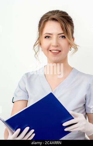 Portrait d'une jeune infirmière en porte-chemise bleue en gants, regardant l'appareil photo sur fond blanc Banque D'Images