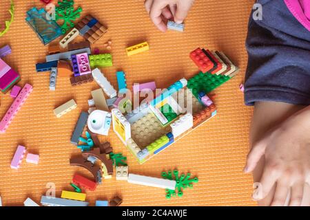 05/15/2020 Russie, Magnitogorsk: Un enfant joue Lego sur un tapis orange Banque D'Images