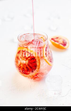 Préparer un cocktail glacé mousseux avec du sang orange sur fond blanc Banque D'Images