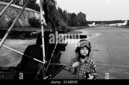 Rêves d'une petite fille sur les vols et les avions UNE petite fille dans un casque de vol se tient près d'un deltaplane avec un moteur. Monino. Ancien aérodrome. Banque D'Images