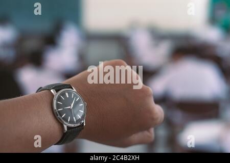 La montre en main de l'enseignant avec l'étudiant qui fait l'examen éducatif en classe Banque D'Images