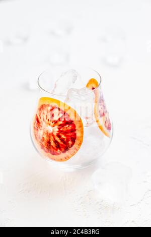 Un verre avec des glaçons et deux tranches d'orange sur fond blanc Banque D'Images