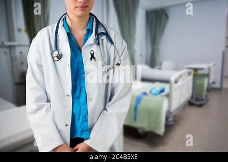 Section médiane de la femme médecin avec ruban noir debout sur la robe debout dans l'hôpital Banque D'Images