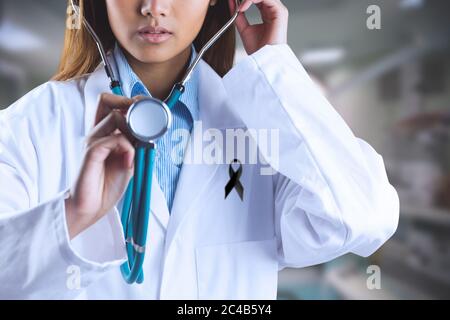 Section moyenne de la femme médecin avec ruban noir utilisant le stéthoscope dans l'hôpital Banque D'Images