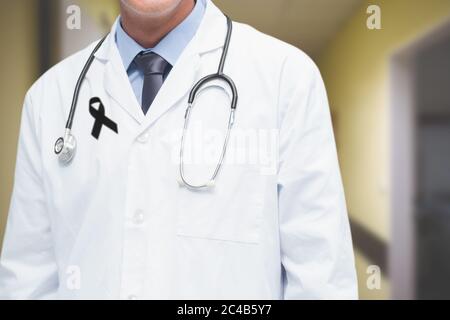 Section médiane du médecin masculin avec ruban noir sur la robe debout à l'hôpital Banque D'Images