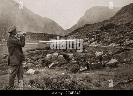 Une scène du guide du Gap of Dunloe au début des années 1920 jouant des airs irlandais sur sa trompette, un peu loin de Kate Kearney's Cottage. C'était une famille dans le parc national de Killarney (aujourd'hui) dans le comté de Kerry. Initialement photographié par Clifton Adams (1890-1934) pour 'Ireland: The Rock Wharce I was hewn', un reportage du magazine National Geographic de mars 1927. Banque D'Images