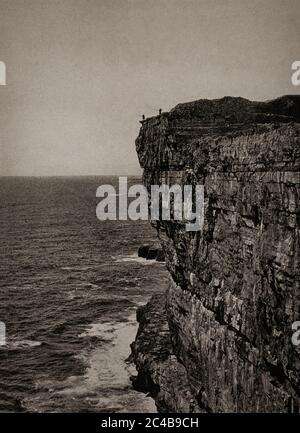 Vue du début des années 1920 sur les pêcheurs de ligne qui attrapent la goberge depuis les falaises d'Inishmore, une des îles d'Aran, comté de Galway. Initialement photographié par A. W. Cutler (1875-1935) pour 'Ireland: The Rock Wharce I was hewn', un reportage du magazine National Geographic de mars 1927. Banque D'Images