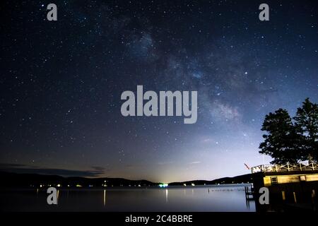 Milky Way Galaxy au-dessus du lac avec pollution lumineuse de la ville entourée par les montagnes Banque D'Images